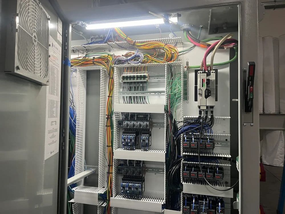 Electrical control cabinet with organized wiring and circuit breakers for efficient management.