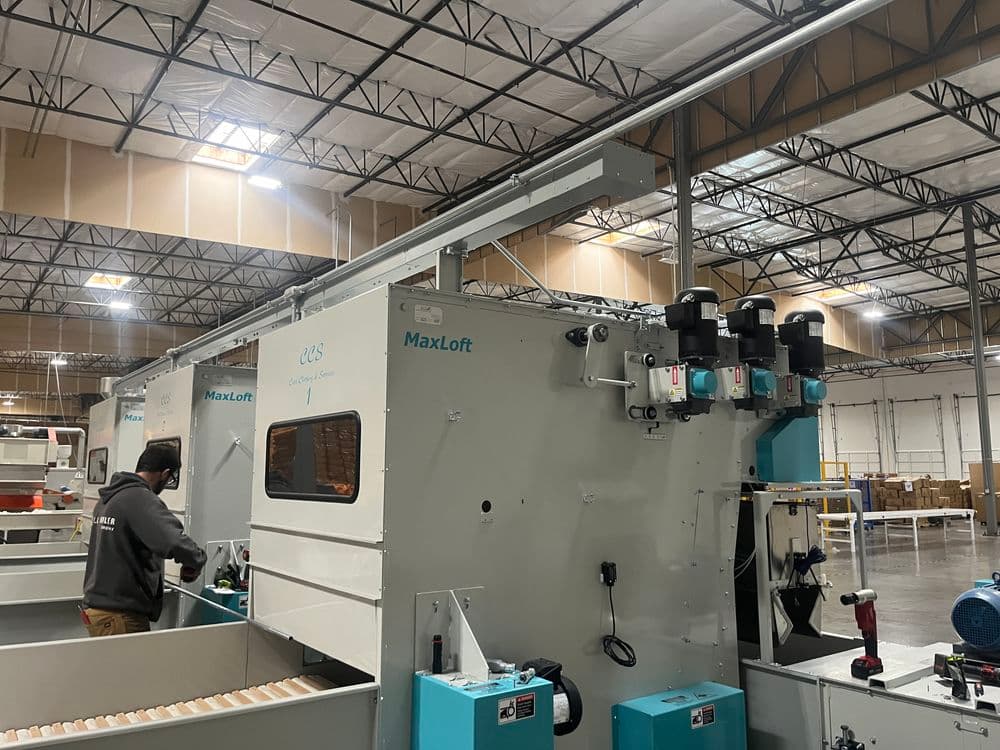 MaxLoft machinery in a warehouse, with an operator working on the equipment.