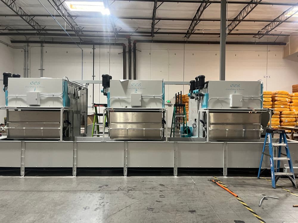 Industrial food processing equipment in a commercial kitchen with stainless steel machines.