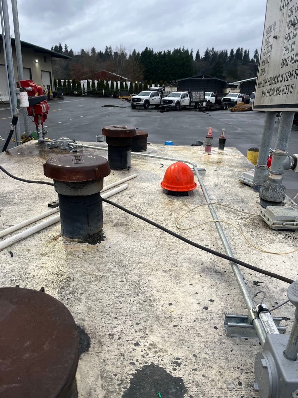 Industrial tank top with safety helmet, valves, and piping at a construction site.