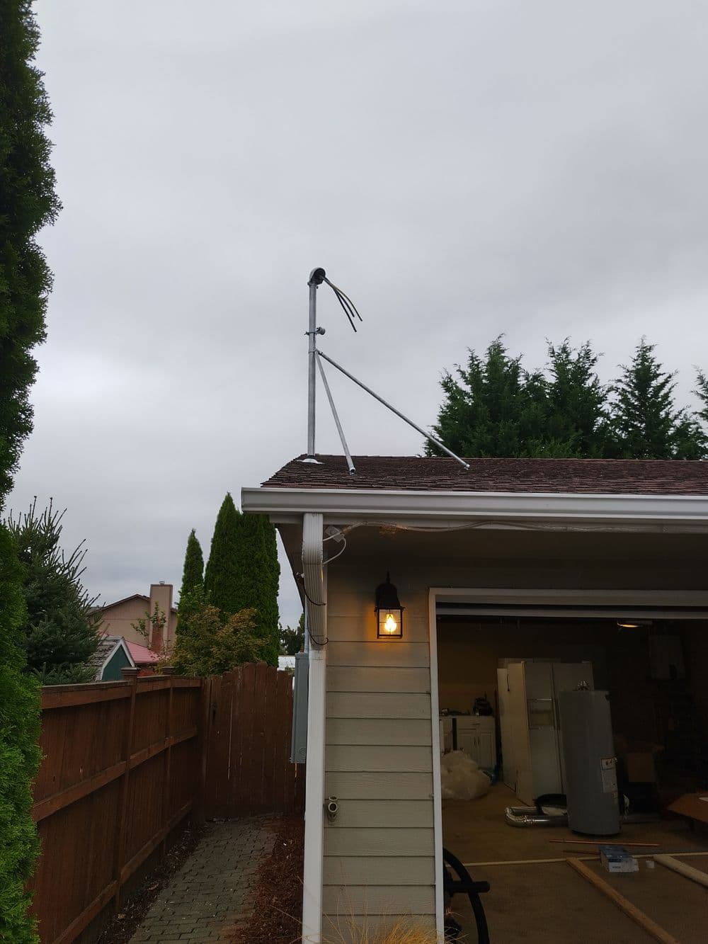 A roof-mounted antenna with support poles against a cloudy sky.