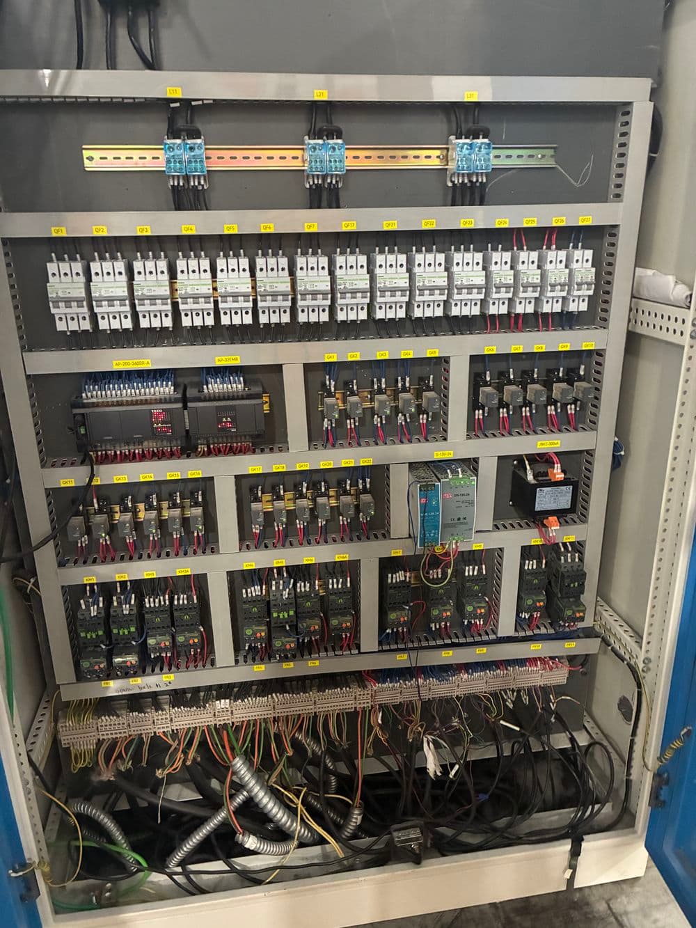 Industrial control panel with labeled circuit breakers and wiring for automation systems.